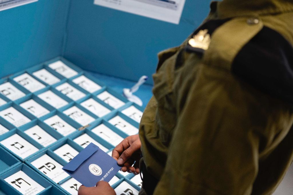Un soldado israelí mirando las papeletas de votación Un soldado israelí mirando las papeletas de votación