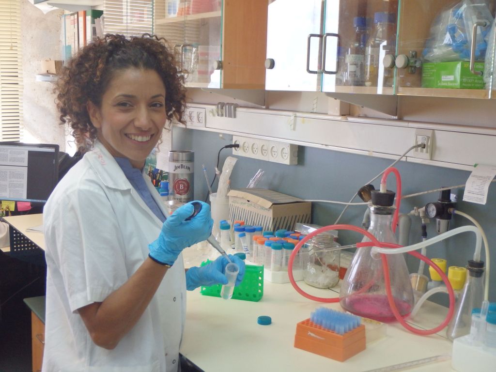 La Profesora Carmit Levy en su laboratorio, de guantes azules, con un tubo de ensayo