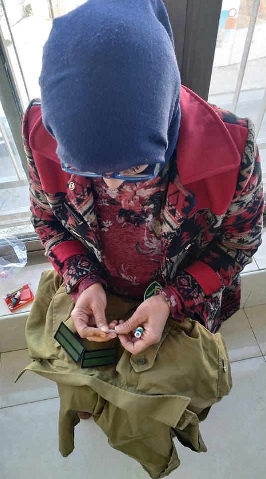 La madre de Yehia cosi&eacute;ndolo los rangos en el uniforme. (Foto en su Facebook)