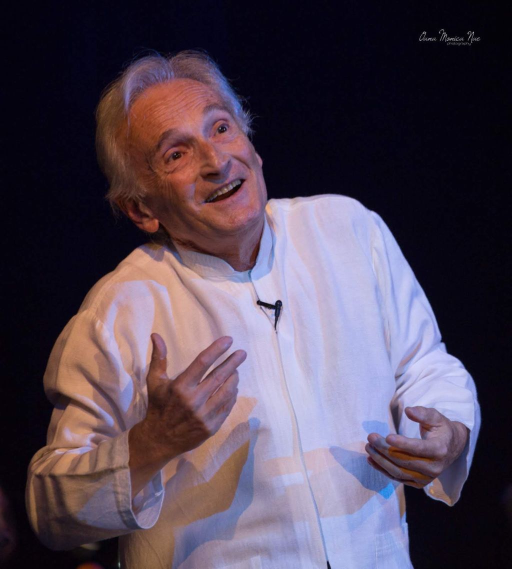 De blanco, gesticulando con rostro y brazos, Rafael Goldwasser sobre el escenario