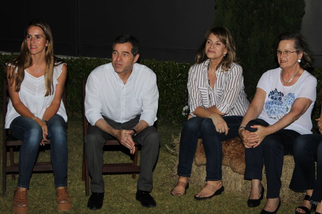 Caro Ache Batlle con un grupo de personas, todos sentados, a la intemperie