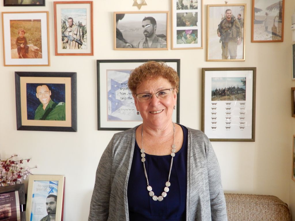 Miriam Peretz junto a la pared de los recuerdos. Miriam Peretz en el comedor de su casa. De fondo, sobre la pared, fotos familiares y de sus hijos caídos.