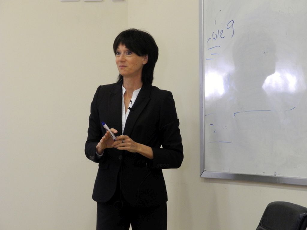 Suzie Navot de pie junto a un pizarrón, sonriente, en clase