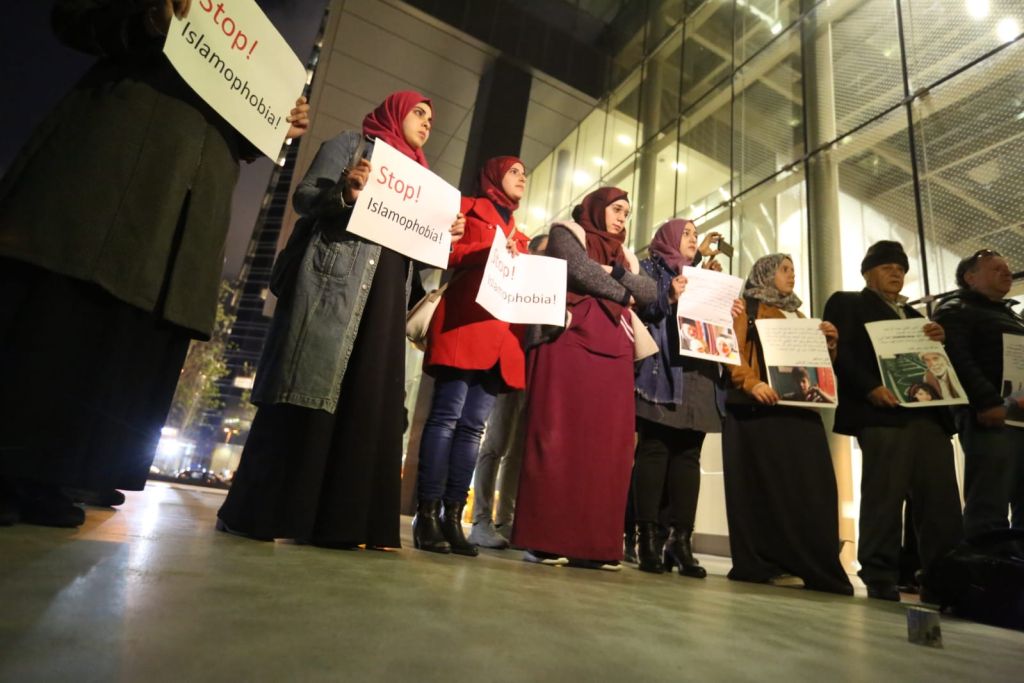 Varias mujeres en línea circular con carteles Stop Islamophobia