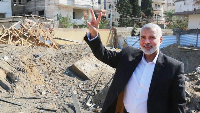 Ismail Haniye sonriente, con señal de victoria, junto a las ruinas de su oficina