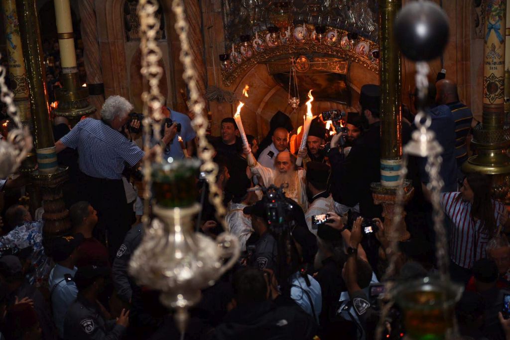 El Patriarca Theophilos III sale del Sepulcro con las velas encendidas
