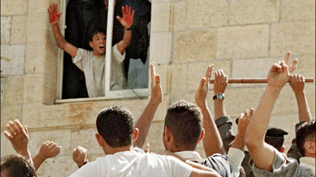 El linchamiento de dos reservistas israelíes en una estación de policía en Ramallah. Uno de los asesinos muestra a la multitud sus manos con sangre de las víctimas.