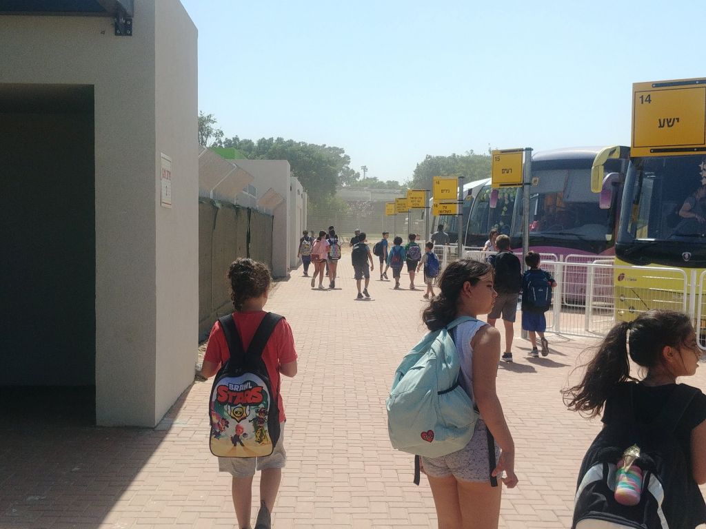 Alumnos de escuela en el Consejo regiona Eshkol, en camino a los autobuses que los llevan a sus respectivos kibutzim o moshavim en la zona, al terminar el día de clases. A la izquierda, estructuras protectoras para refugiarse si los sorprende la alarma.