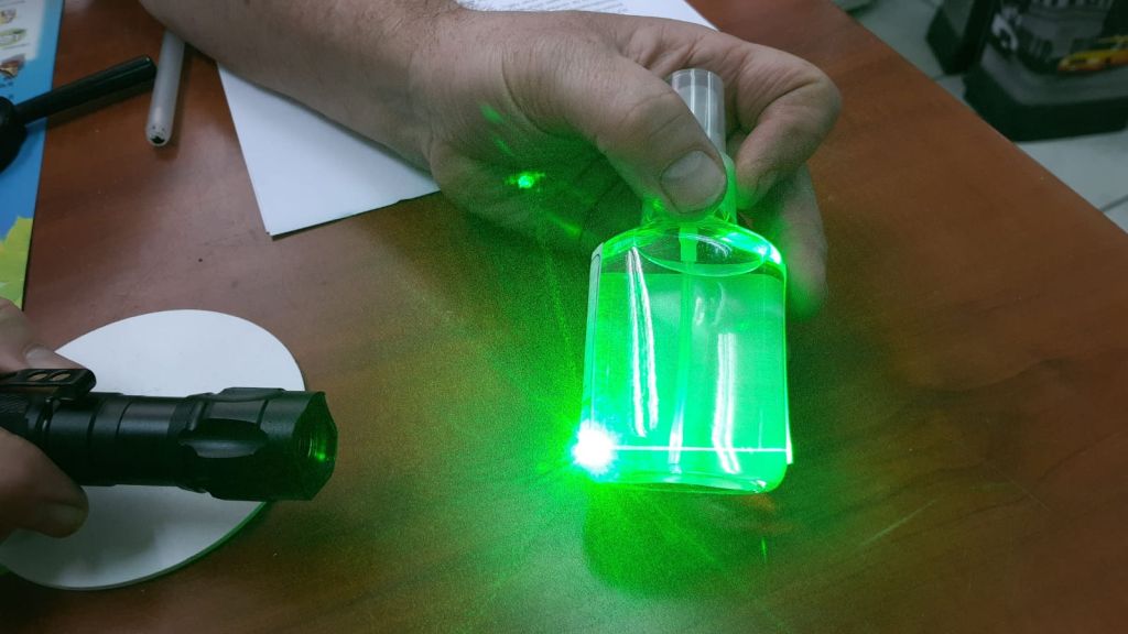 ¿Cómo sabemos que no es simplemente agua embotellada y no nos están engañando? Si fuera agua, se vería transparente también al iluminar  el frasco con un rayo laser, sencillo, como el usado por ejemplo para señalar una pizarra en una conferencia, que sería impercetible en el agua. Pero dado que tiene partículas de plata, esta es la reacción que produce el laser.