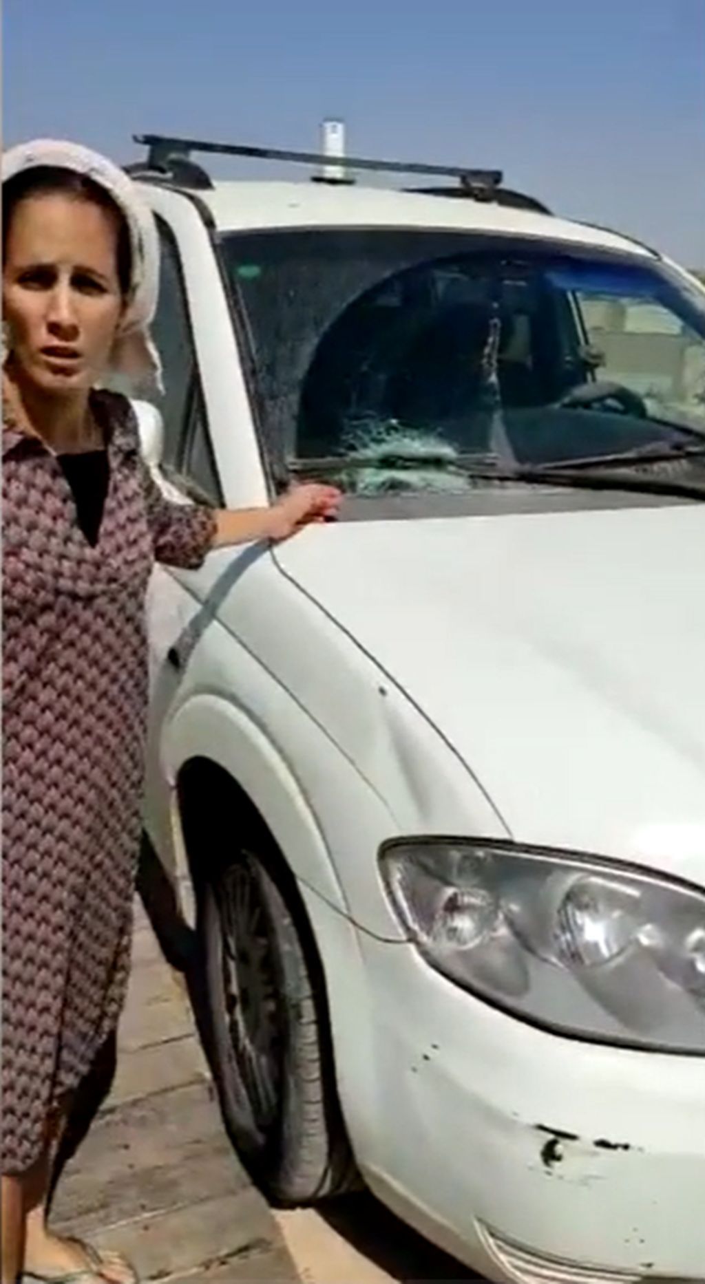 Renana Peretz mostrando el impacto de la piedra en el vidrio de su auto