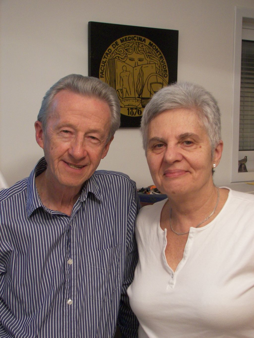 Rosa y Jaime en su casa anterior. De fondo, el símbolo de la Facultad de Medicina de la UdelaR