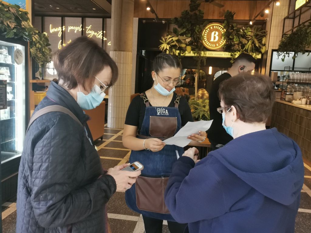 Una empleada en el café Biga pide constancia de vacunación a dos comensales