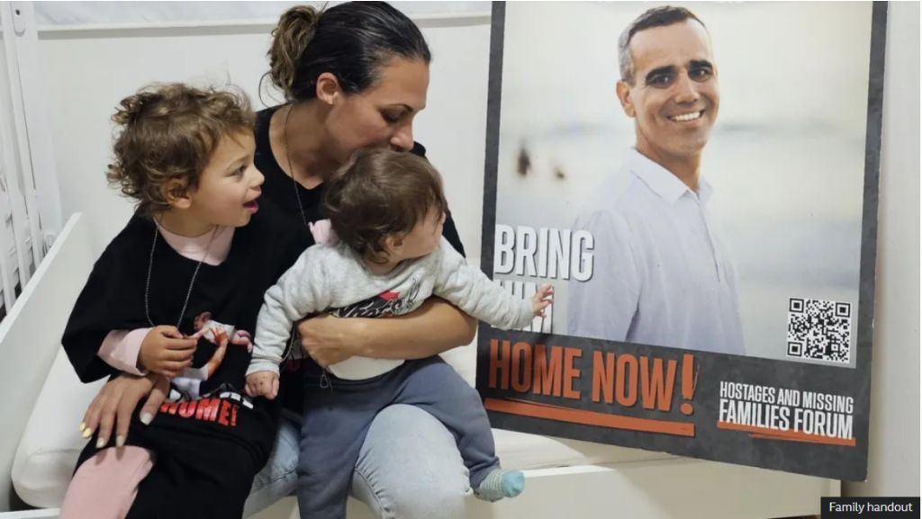 Lishay, la esposa de Omri, con las dos hijas de ambos, esperándolo sin cesar, aquí junto al poster del Foro de Familiares de los Secuestrados (Gentileza de la familia)