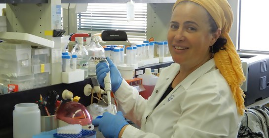 La Dra. Regina Gerstl en el laboratorio, con guantes y tubos en la mano.