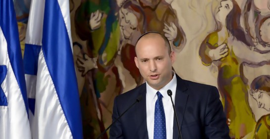 El ministro israelí Naftali Bennett hablando junto a dos banderas de Israel. De fondo, murales de Chagall en el parlamento israelí