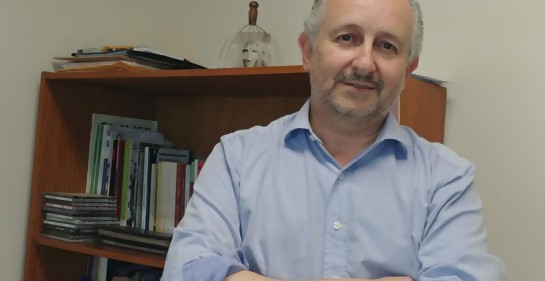 Pablo da Silveira, de brazos cruzados, mirando de fondo a la cámara. De fondo, una bibilioteca con libros.