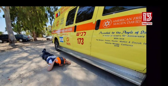 Un paramédico sorprendido por una alarma en el sur de Israel, cumpliendo instrucciones: si no hay refugio cerca, tirarse al suelo y protegerse la cabeza(captura de pantalla canal 11 tv israelí)