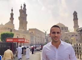 Yonatan Gonen, de camisa blanca, de fondo la calle, transeúnes, hermosos edificios
