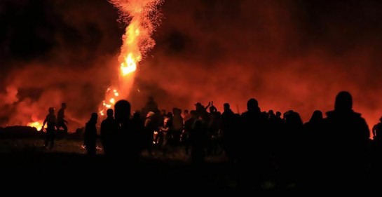 Aglomeración de palestinos en la frontera de Gaza con Israel, fuego de fondo