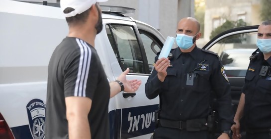 Un policía entregando una máscara a un ciudadano