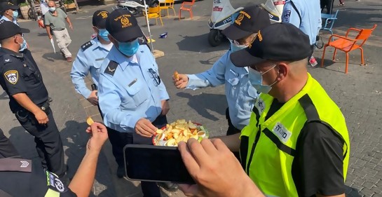 Policías uniformados reciben trozos de manzana con miel