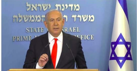 El Primer Ministro de Israel, de traje, en un podio, con la bandera de israel a su lado