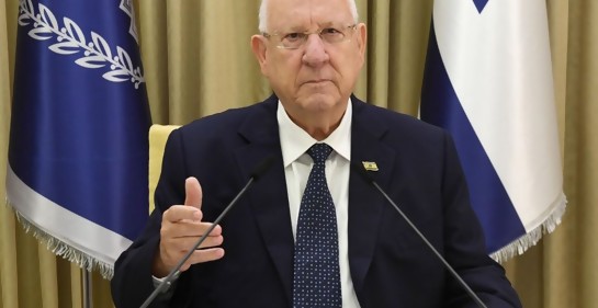 El PResidente Rivlin, sentado, de fondo bandera de Israel y bandera de Beit HaNasí