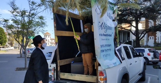 Una camioneta de base de una cabaña , un rabino afuera, una mujer adentro haciendo una bendición con especies