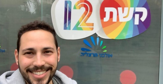Freddy sonriente, de fondo el logo en hebreo keshet 12, la televisión