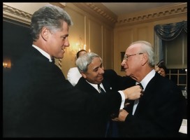 Clinton y Eitan Haber arreglan la corbata de Rabin, sonriente