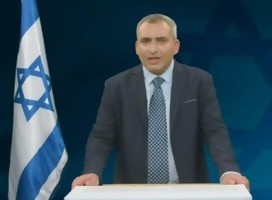 El ministro Elkin hablando, a su lado, una bandera de Israel