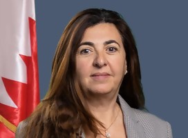 Mujer, mirando de frente, con la bandera de Bahrein a su izquierda