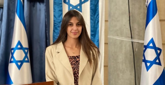 Una joven mirando a la cámara, rodeada de banderas de Israel