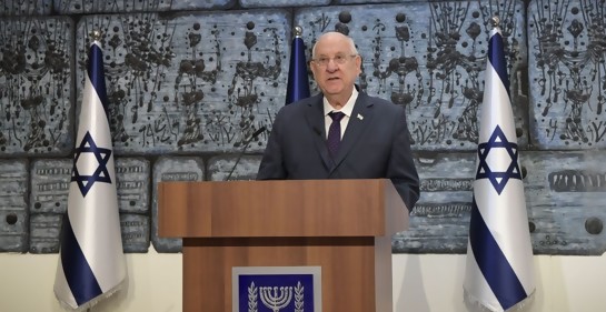 Rivlin de pie, en podio de oradores con el escudo de Israel, de fondo una obra de arte a sus dos costados, la bandera de Israel