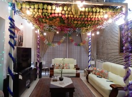 Un comedor, sillones, mesa, paredes adornadas, y bajo el techo, una artesanía de frutas entrelazadas como techo de la cabaña interior