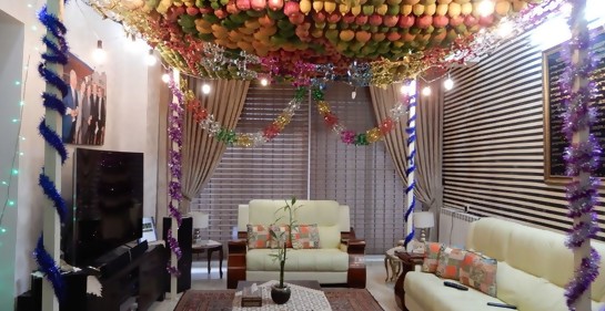 Un comedor, sillones, mesa, paredes adornadas, y bajo el techo, una artesanía de frutas entrelazadas como techo de la cabaña interior