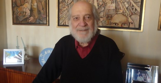 Biriotti, sonriente, junto a un aparador, de fondo dos cuadros